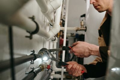 Technician inspecting commercial plumbing pipes in Hayward